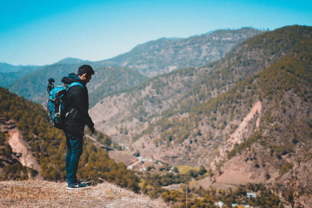 man backpacking through nature on a mountain